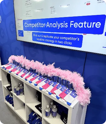 Articles promotionnels Collaborator disposés sous un écran présentant la fonctionnalité « Analyse des concurrents » lors du BrightonSEO 2025.