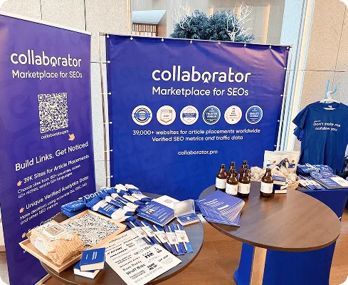 Stand de Collaborator avec des bannières aux couleurs de la marque, des articles promotionnels, des livres et des boissons au Baltic-Nordic SEO Summit 2026.